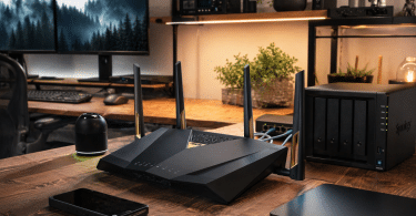 Routeur ASUS RT-BE88U installé dans un bureau domestique avancé avec NAS, écran et réseau local rapide