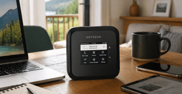 Routeur mobile NETGEAR Nighthawk M6 posé sur une table en bois à côté d’un ordinateur portable, d’un smartphone, d’une tablette, d’un carnet et d’une tasse