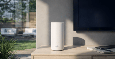 Système WiFi mesh NETGEAR Orbi RBE773 posé sur un meuble dans un salon lumineux