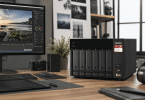 NAS QNAP TS-673A-8G posé sur un bureau de création avec écran, matériel photo et espace de travail organisé