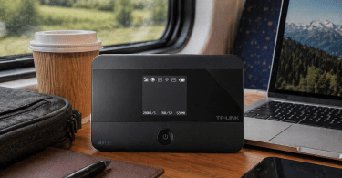 Routeur mobile TP-Link M7350 posé sur une table de train à côté d’un ordinateur portable, d’un smartphone, d’un carnet et d’un café